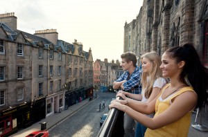 Grassmarket, a historic street in Edinburgh. Three young people on the terrace overlooking the street and terraced houses.