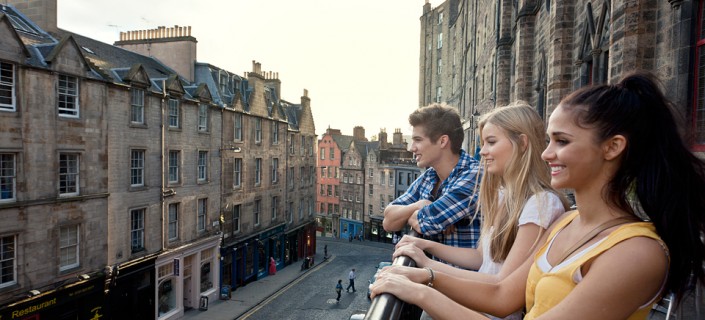 Grassmarket, a historic street in Edinburgh. Three young people on the terrace overlooking the street and terraced houses.
